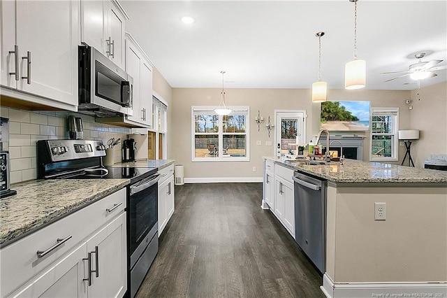 kitchen with appliances with stainless steel finishes, sink, a center island with sink, white cabinetry, and hanging light fixtures