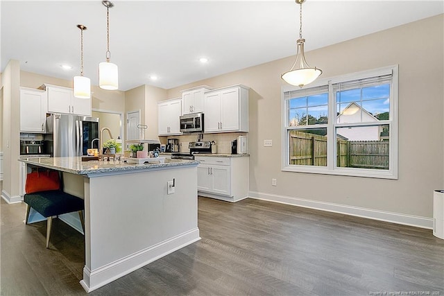 kitchen featuring pendant lighting, stainless steel appliances, and a kitchen island with sink