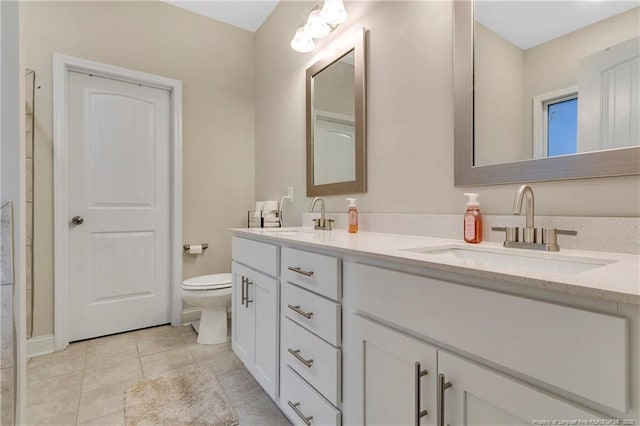 bathroom with toilet, vanity, and tile patterned floors