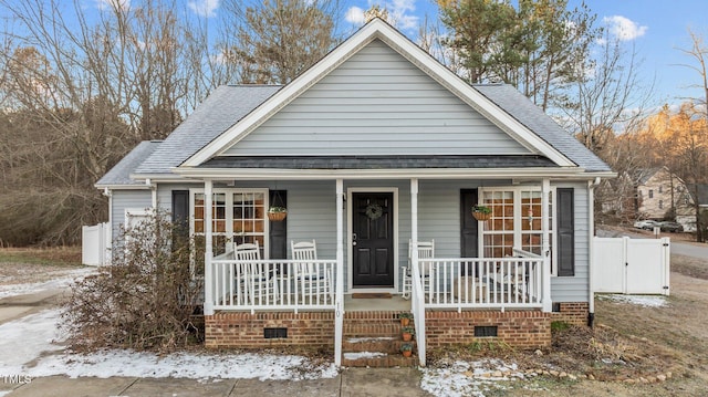 bungalow-style home with crawl space, covered porch, and roof with shingles