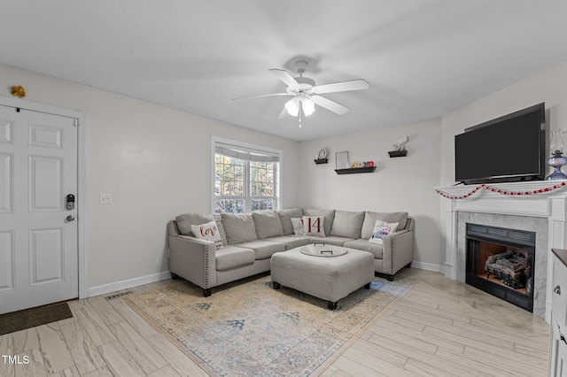 living area featuring a fireplace, wood finished floors, a ceiling fan, and baseboards