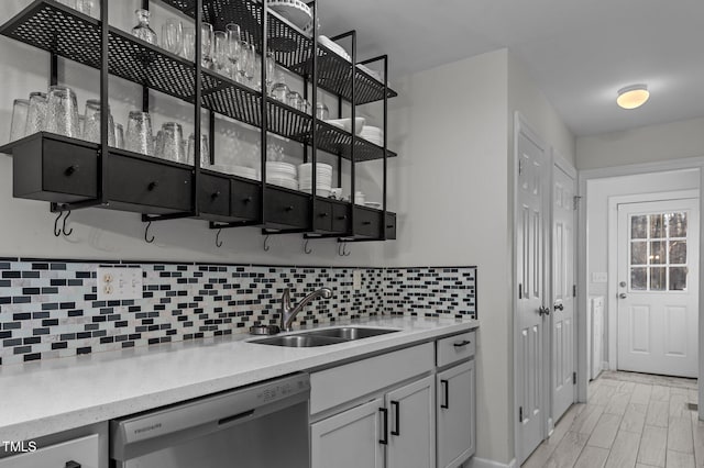 kitchen with light countertops, backsplash, a sink, light wood-type flooring, and dishwasher