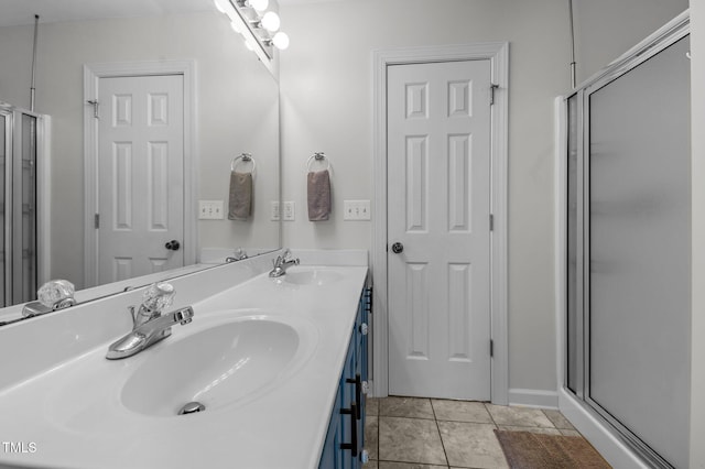 full bathroom featuring double vanity, a shower with door, tile patterned flooring, and a sink