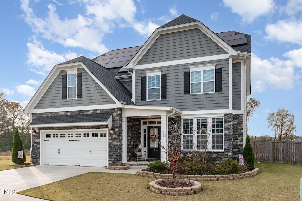 craftsman house with solar panels, a garage, and a front yard