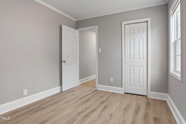 unfurnished bedroom featuring light hardwood / wood-style floors, multiple windows, a closet, and ornamental molding