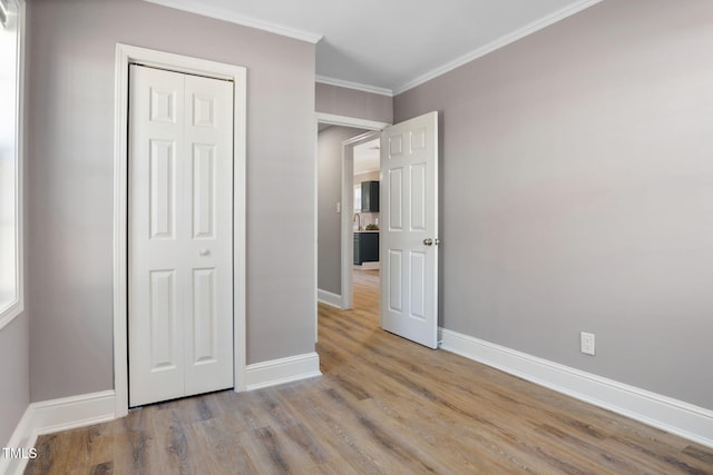 unfurnished bedroom with light wood-type flooring, a closet, and crown molding