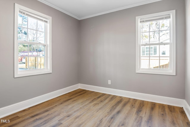 empty room with a wealth of natural light, ornamental molding, and hardwood / wood-style flooring