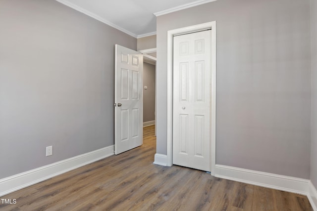 unfurnished bedroom with hardwood / wood-style floors, a closet, and crown molding