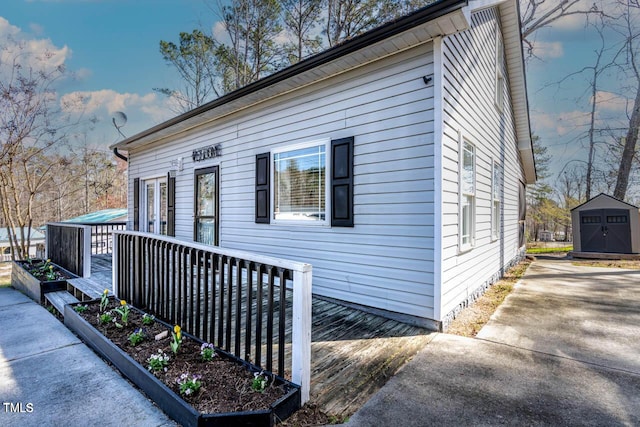 view of side of property with a deck and a storage shed