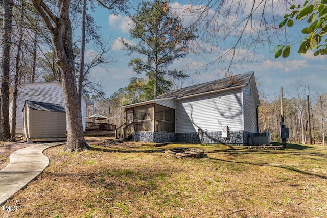 view of side of home featuring a yard, a shed, and a sunroom