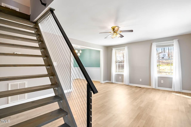 staircase featuring ceiling fan with notable chandelier and hardwood / wood-style flooring