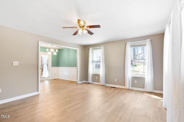 unfurnished room with ceiling fan with notable chandelier and light wood-type flooring