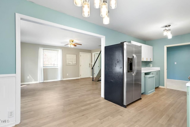 kitchen featuring stainless steel fridge, light hardwood / wood-style flooring, white cabinets, and ceiling fan with notable chandelier