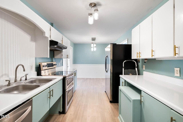 kitchen featuring white cabinets, sink, hanging light fixtures, light wood-type flooring, and stainless steel appliances