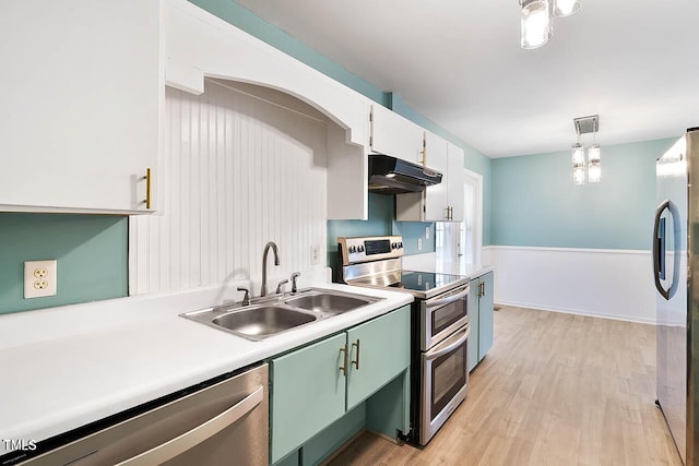 kitchen featuring white cabinetry, sink, stainless steel appliances, light hardwood / wood-style flooring, and decorative light fixtures