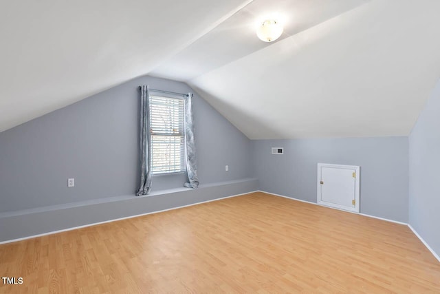 additional living space featuring light wood-type flooring and vaulted ceiling