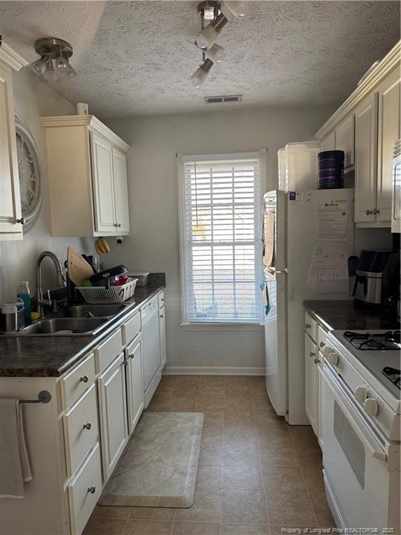 kitchen featuring a textured ceiling, white appliances, white cabinetry, and sink