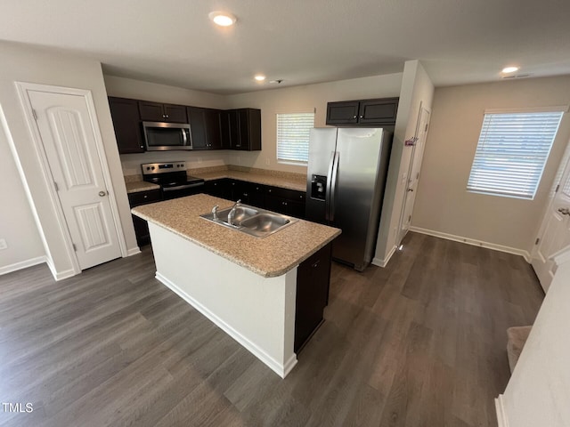 kitchen with dark wood-type flooring, a kitchen island with sink, sink, and stainless steel appliances