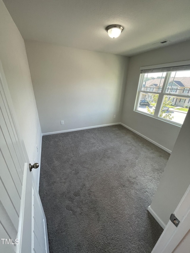 spare room with dark carpet