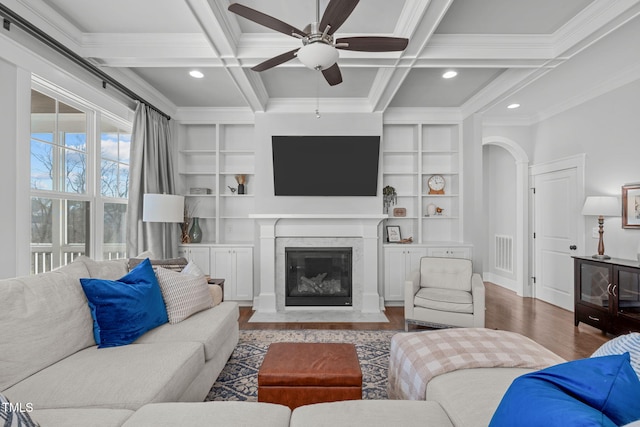 living room with beam ceiling, a premium fireplace, built in features, and coffered ceiling