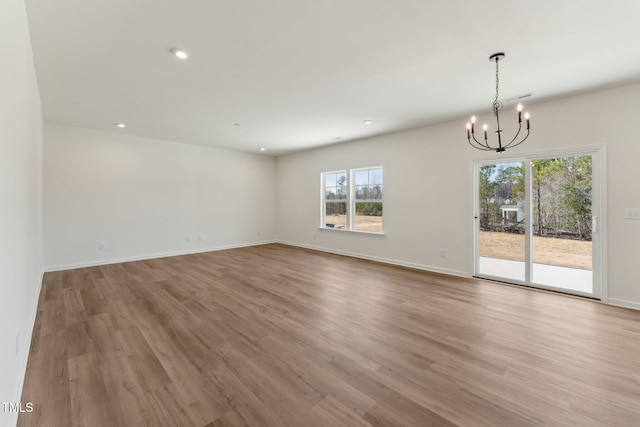 unfurnished room with an inviting chandelier and light hardwood / wood-style floors