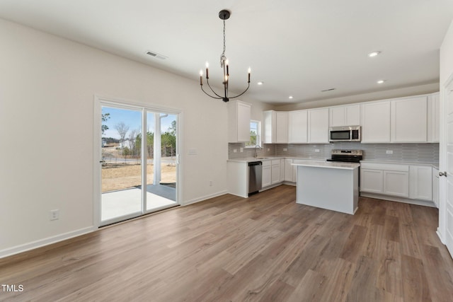 kitchen featuring a kitchen island, appliances with stainless steel finishes, pendant lighting, white cabinets, and decorative backsplash