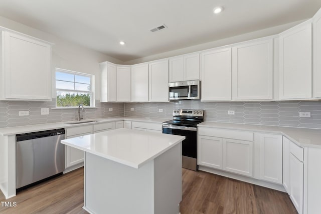 kitchen featuring sink, white cabinetry, stainless steel appliances, tasteful backsplash, and a kitchen island