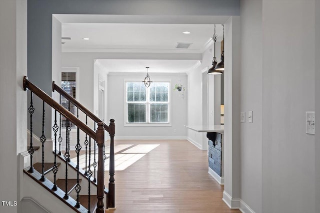 foyer with crown molding and light hardwood / wood-style flooring