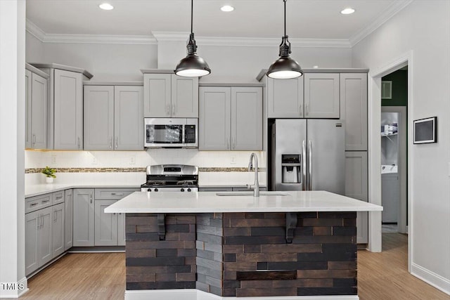 kitchen with sink, decorative light fixtures, gray cabinets, stainless steel appliances, and a kitchen island with sink