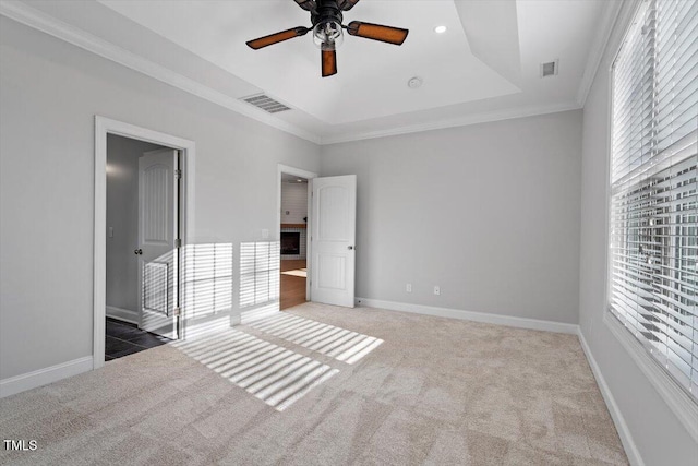 unfurnished bedroom with crown molding, carpet floors, a raised ceiling, and ceiling fan