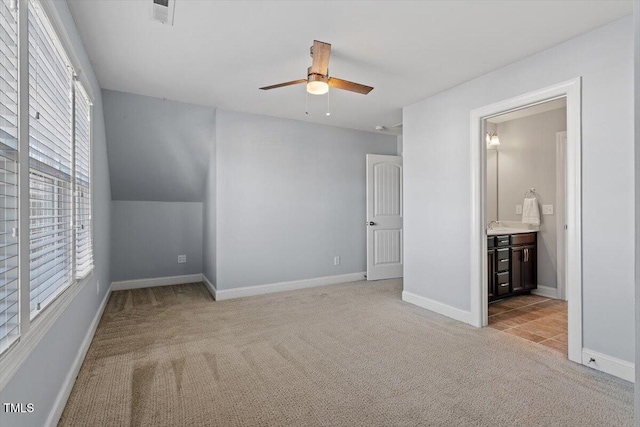 unfurnished bedroom featuring lofted ceiling, light carpet, ceiling fan, and ensuite bath