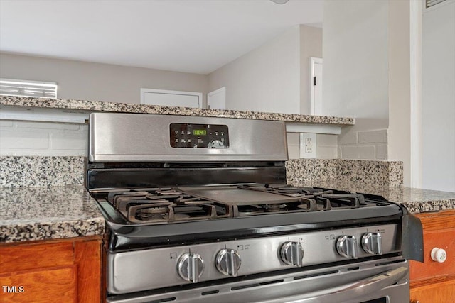 kitchen featuring backsplash, stainless steel range with gas cooktop, and light stone countertops