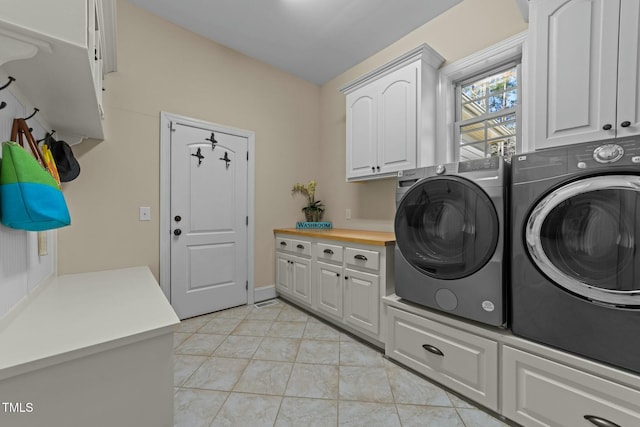 clothes washing area featuring light tile patterned floors, cabinets, and independent washer and dryer