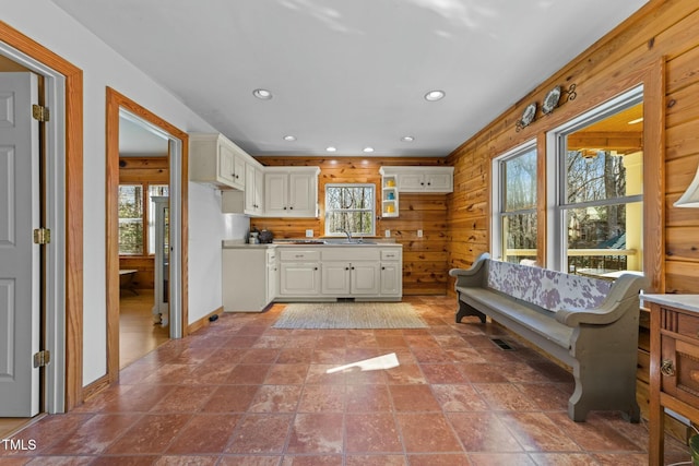 kitchen with sink, wooden walls, and white cabinetry