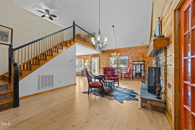 living room featuring ceiling fan with notable chandelier, a fireplace, high vaulted ceiling, and light hardwood / wood-style floors