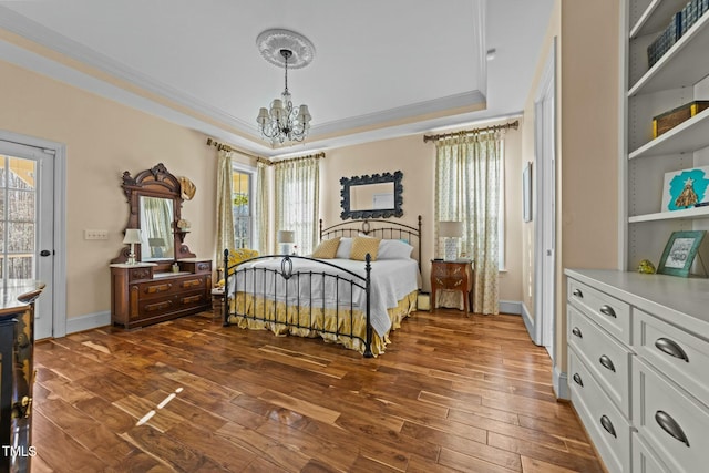 bedroom featuring dark wood-type flooring, a tray ceiling, a chandelier, and multiple windows