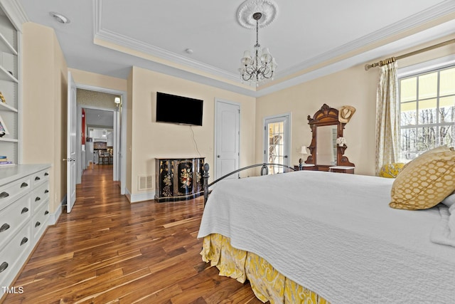 bedroom featuring ornamental molding, dark hardwood / wood-style flooring, a chandelier, and a tray ceiling