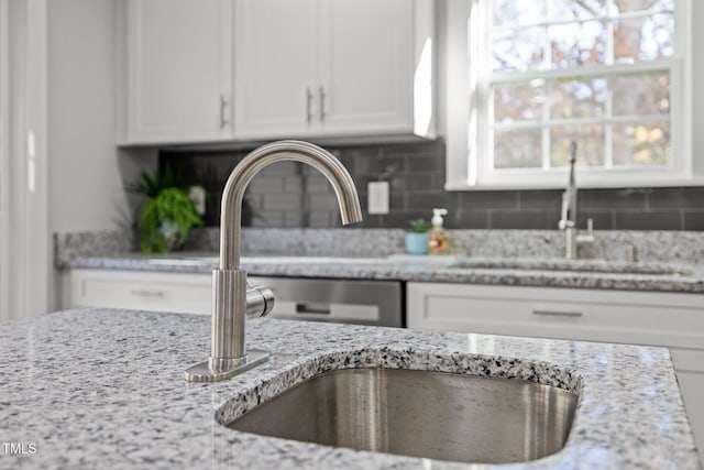 interior space with sink, light stone counters, and white cabinetry