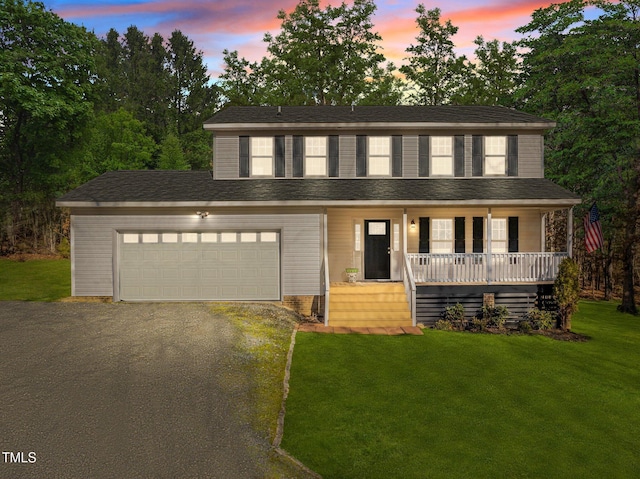 view of front facade with a garage, a lawn, and a porch