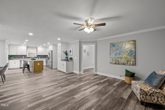 interior space featuring white cabinetry, stainless steel appliances, a kitchen breakfast bar, ornamental molding, and a center island