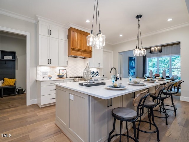 kitchen featuring pendant lighting, white cabinets, tasteful backsplash, light hardwood / wood-style floors, and a large island