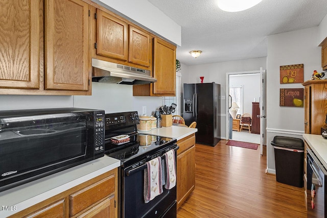 kitchen featuring black appliances, a textured ceiling, and light hardwood / wood-style flooring