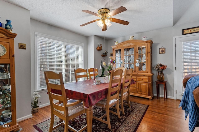 dining area featuring ceiling fan, dark wood-type flooring, and a textured ceiling