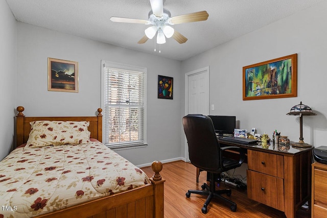 bedroom with ceiling fan, wood-type flooring, and a textured ceiling