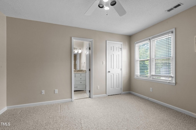 unfurnished bedroom with connected bathroom, ceiling fan, light colored carpet, a textured ceiling, and a closet