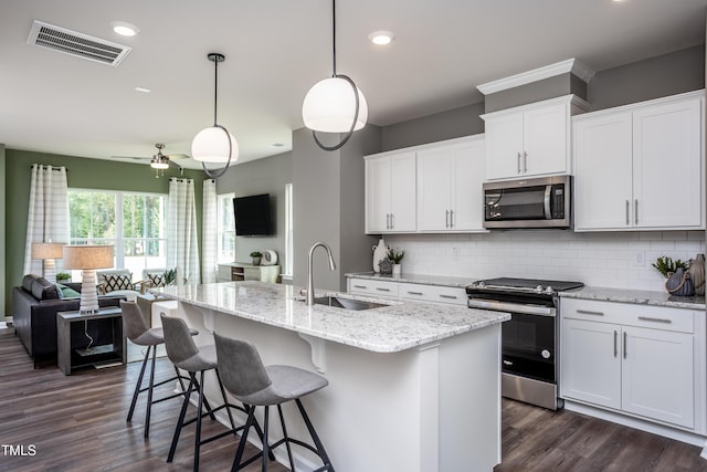 kitchen with pendant lighting, a center island with sink, white cabinets, and stainless steel appliances