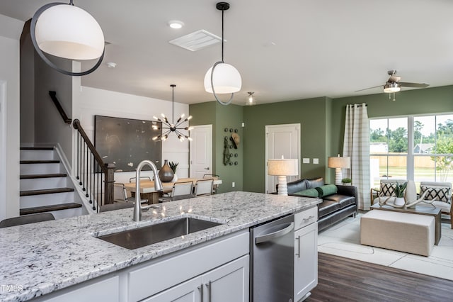 kitchen with sink, hanging light fixtures, stainless steel dishwasher, white cabinets, and ceiling fan with notable chandelier