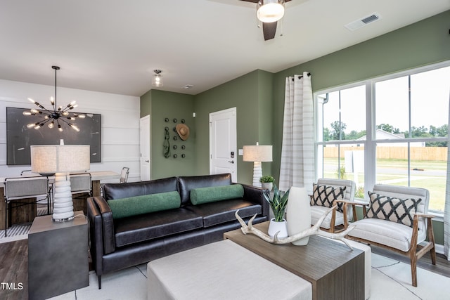 living room with ceiling fan with notable chandelier and light hardwood / wood-style flooring