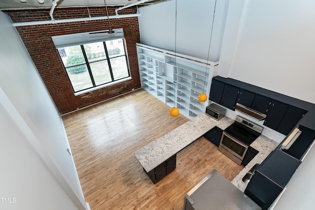 unfurnished living room with light hardwood / wood-style flooring and brick wall