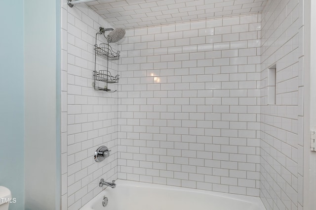 bathroom featuring toilet and tiled shower / bath